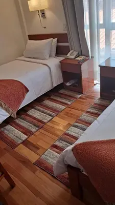 a hotel room with two beds and a rug at Xima Cusco Kenamari in Cusco