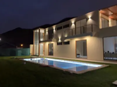 a house with a swimming pool in front of it at night at House 3M in Condominium Fundo Pradera, Chocaya - Lima - Perú in Asia