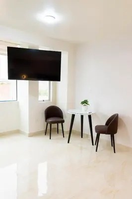 a room with two chairs and a table and a tv at Solay Inn in Ayacucho