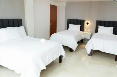 a room with three beds with white sheets and a door at Solay Inn in Ayacucho