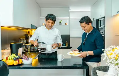 two men standing in a kitchen preparing food at Departamento Illapa in Cusco