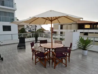 a table and chairs with an umbrella on a balcony at Duplex - Playa Embajadores in Quebrada Seca