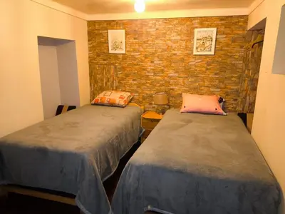 a room with two beds and a brick wall at Victoria home in Cusco