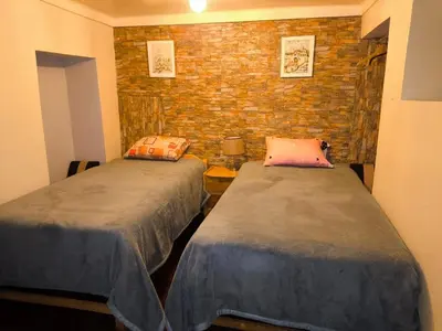 a room with two beds and a brick wall at Victoria home in Cusco