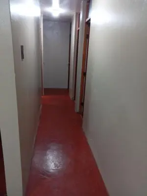 a hallway with a red floor and white walls at Departamento 2 dormitorios 4B in Lima