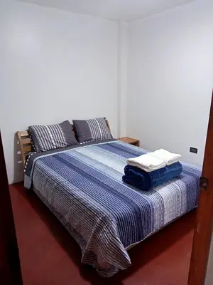 a bedroom with a bed with a blue blanket and pillows at Departamento 2 dormitorios 4B in Lima