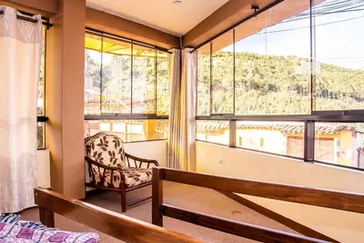 a room with a chair and large windows at Departamentos Santa Ana Barrio Tradicional in Cusco