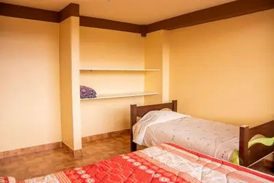 a room with two beds and a shelf at Departamentos Santa Ana Barrio Tradicional in Cusco