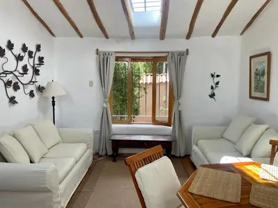 a living room with white furniture and a window at Kusi Qente in Cusco