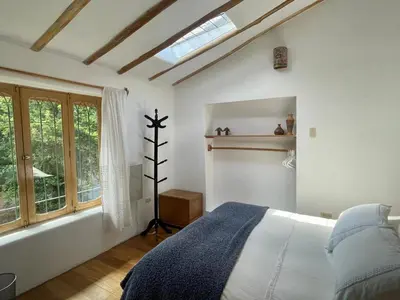 a white bedroom with a bed and a window at Kusi Qente in Cusco