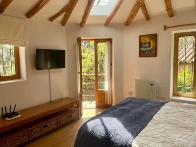 a bedroom with a bed and a flat screen tv at Kusi Qente in Cusco