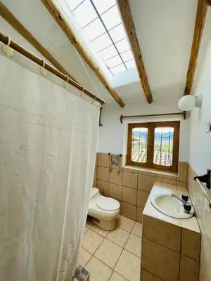 a bathroom with a toilet and a sink and a window at Kusi Qente in Cusco