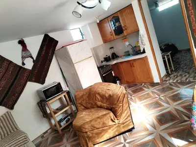 a living room with a chair and a kitchen at Encanto del Cusco in Cusco