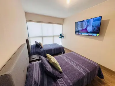 a bedroom with two beds and a flat screen tv at M15 - Two Bedroom Apartment in front of the US Embassy in Lima