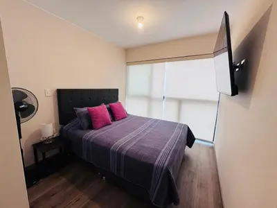 a bedroom with a bed with two pink pillows at M15 - Two Bedroom Apartment in front of the US Embassy in Lima