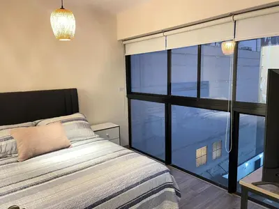 a bedroom with a bed and a large window at M24 Departamento de 2 Dorm 2 baños - Frente Embajada de USA in Lima
