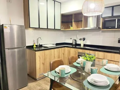 a kitchen with a table and a stainless steel refrigerator at M24 Departamento de 2 Dorm 2 baños - Frente Embajada de USA in Lima