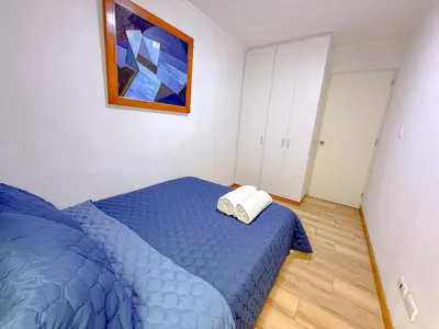 a bedroom with a blue bed and a painting on the wall at Amplio depa 3 habitaciones en Costanera in Lima