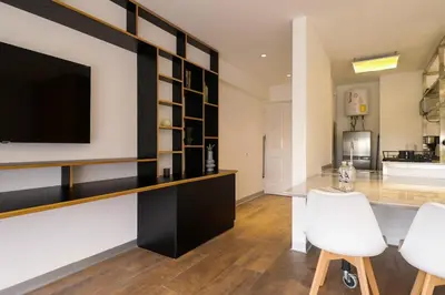 a living room with a television and white chairs at Moderno apartamento en San Isidro in Lima