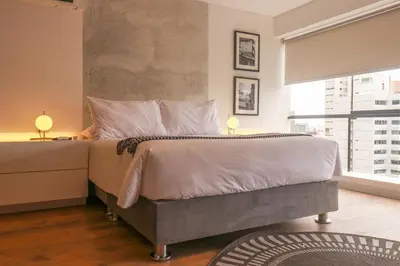 a bedroom with a large bed with white sheets and pillows at Moderno apartamento en San Isidro in Lima