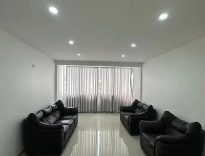 a living room with two leather couches and a window at Hotel Altavista in Abancay