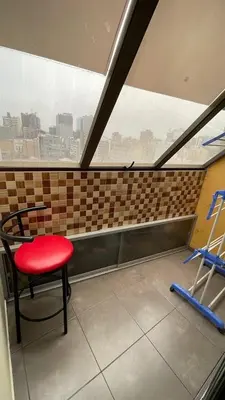 a red chair sitting in front of a window at A cozy apartment in the heart of Miraflores in Lima