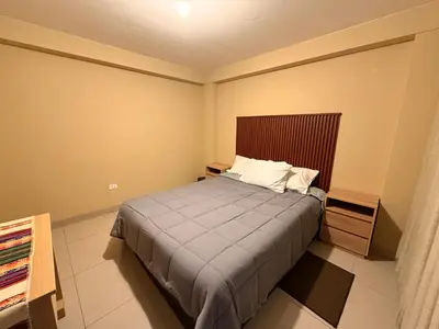 a bedroom with a bed with a wooden headboard at Tres Cruces Private Rooms in Cusco