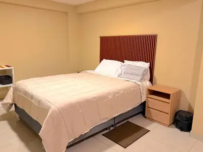 a bedroom with a bed and a wooden night stand at Tres Cruces Private Rooms in Cusco