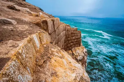a stone wall next to the ocean on a cliff at Casa de playa en Cerro Azul con piscina privada in Cerro Azul