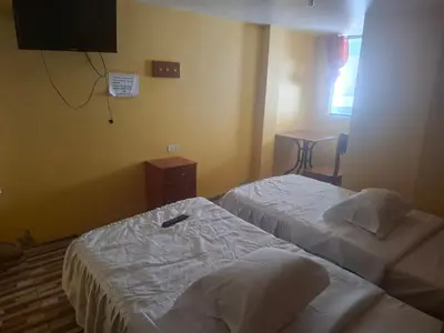 a hotel room with two beds and a television at Hospedaje Las Brisas in Churín