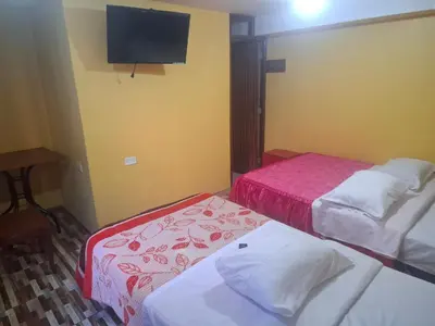 a room with two beds and a flat screen tv at Hospedaje Las Brisas in Churín
