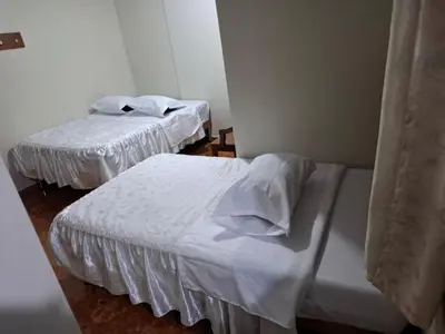 two beds with white sheets in a room at Hospedaje Las Brisas in Churín
