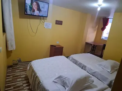 two beds in a room with a tv on the wall at Hospedaje Las Brisas in Churín