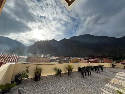 a balcony with chairs and a view of mountains at Qhawarina Hostel Ollantaytambo in Ollantaytambo