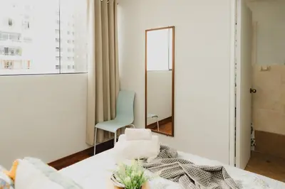 a bedroom with a mirror and a green chair at Galvez 3 Dormitorios by Casa Miraflores - Wifi Washer Hot Water in Lima