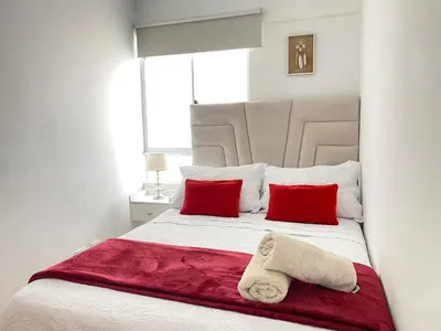 a bedroom with a white bed with red pillows at Mendiburu 2 Dormitorios by Casa Miraflores - Wifi - Hot Water in Lima