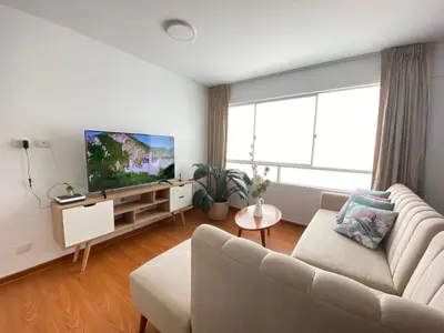 a living room with a couch and a flat screen tv at Mendiburu 2 Dormitorios by Casa Miraflores - Wifi - Hot Water in Lima
