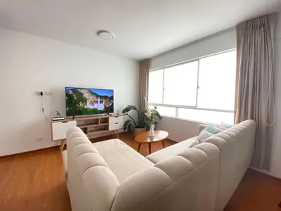a living room with a white couch and a tv at Mendiburu 2 Dormitorios by Casa Miraflores - Wifi - Hot Water in Lima