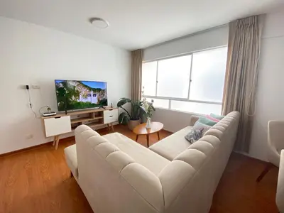 a living room with a white couch and a large window at Mendiburu 2 Dormitorios by Casa Miraflores - Wifi - Hot Water in Lima