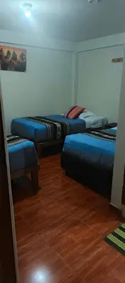 three beds in a room with a wooden floor at AMARU Palace in Machu Picchu