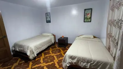 a bedroom with two beds and a table with a night stand at Victoria home san blas in Cusco