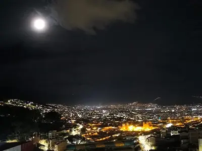 a view of a city at night with the moon at Santa Ana Home Cusco in Cusco