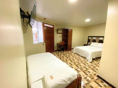 a bedroom with two beds and a tiled floor at Hotel Leal in Ayacucho