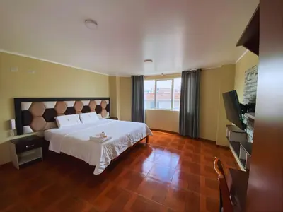 a bedroom with a large white bed and a television at Hotel Leal in Ayacucho