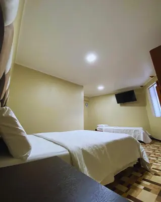 a hotel room with two beds and a television at Hotel Leal in Ayacucho