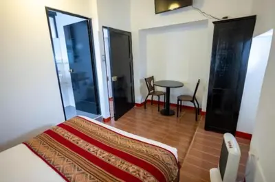 a bedroom with a bed and a table and chairs at San Blas Plaza Hotel in Cusco