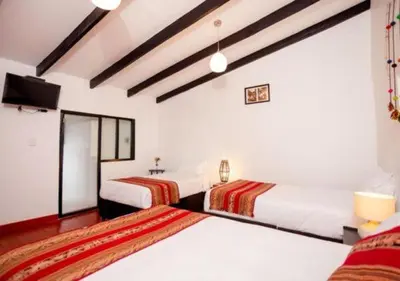 a room with two beds and a television in it at San Blas Plaza Hotel in Cusco
