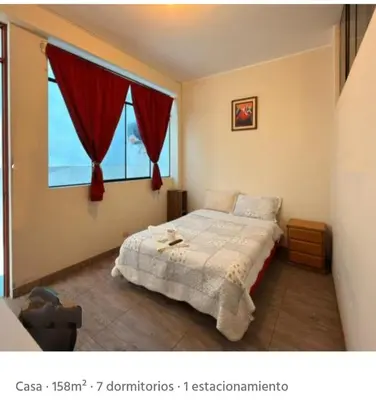 a bedroom with a bed and a window with red curtains at CHANCAY- 1er PISO DEPARTAMENTO in Chancay