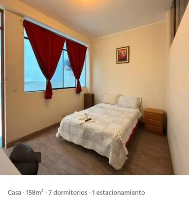 a bedroom with a bed and a window with red curtains at CHANCAY- 1er PISO DEPARTAMENTO in Chancay