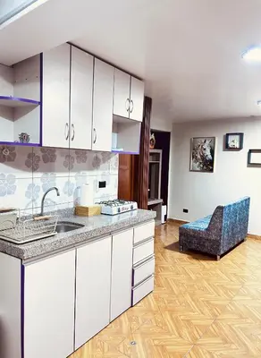 a kitchen with white cabinets and a blue chair at Casa de Paz in Cusco